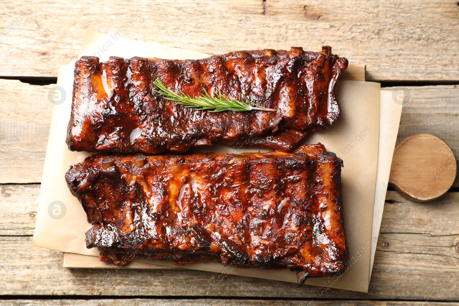 Tasty roasted pork ribs served with rosemary on wooden table, top view Photo of Tasty roasted pork ribs served with rosemary on wooden table, top view