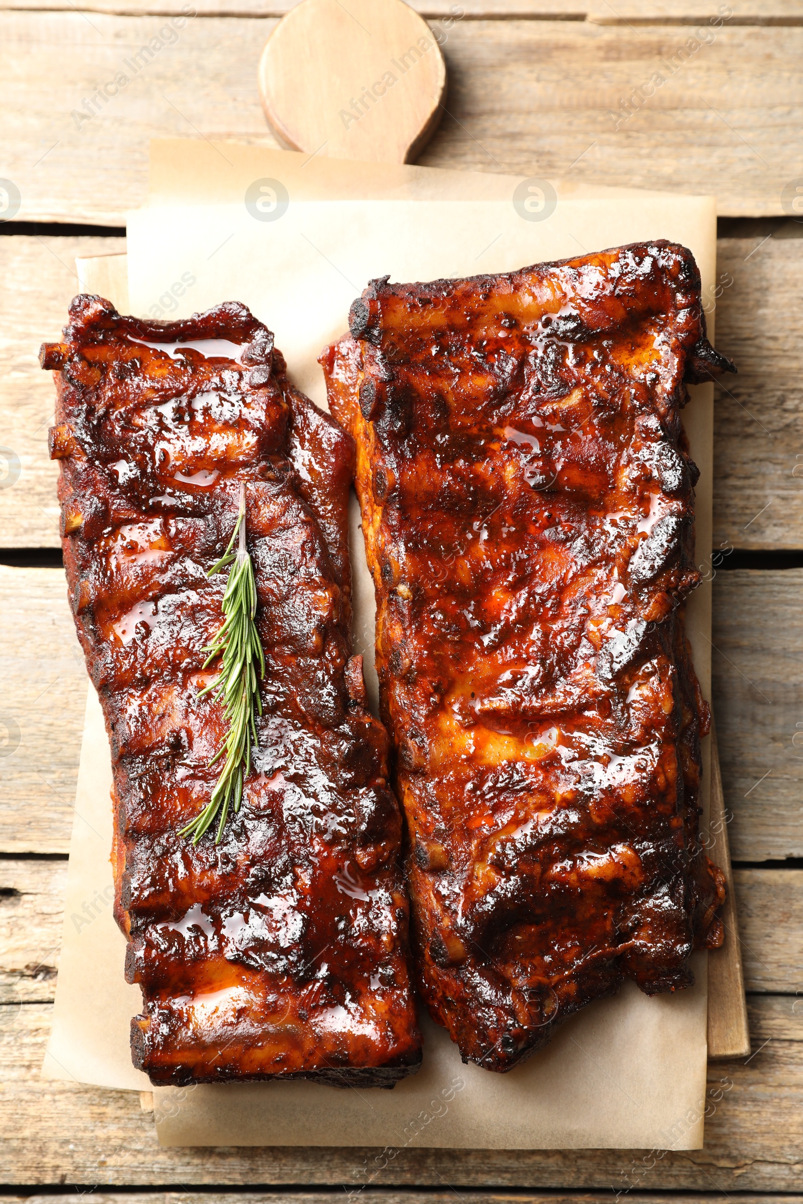 Tasty roasted pork ribs served with rosemary on wooden table, top view Photo of Tasty roasted pork ribs served with rosemary on wooden table, top view