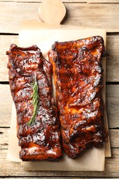 Photo of Tasty roasted pork ribs served with rosemary on wooden table, top view
