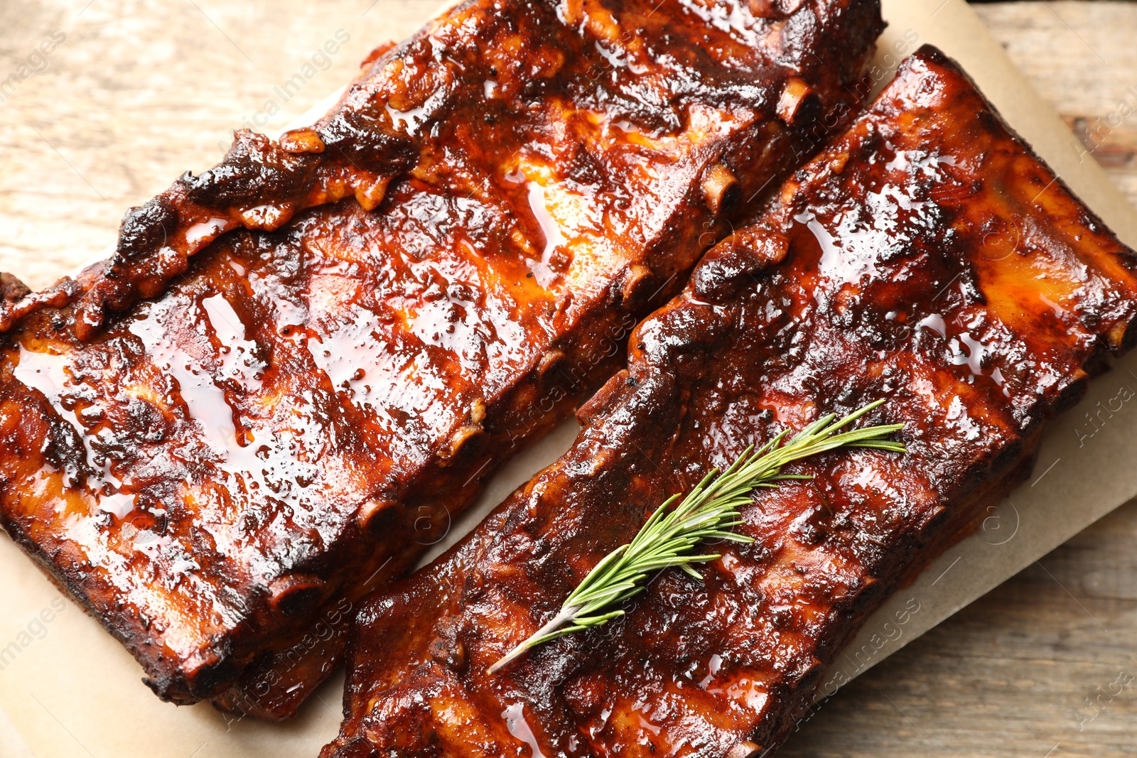 Tasty roasted pork ribs served with rosemary on wooden table, top view Photo of Tasty roasted pork ribs served with rosemary on wooden table, top view