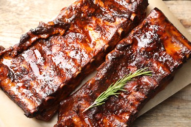 Photo of Tasty roasted pork ribs served with rosemary on wooden table, top view