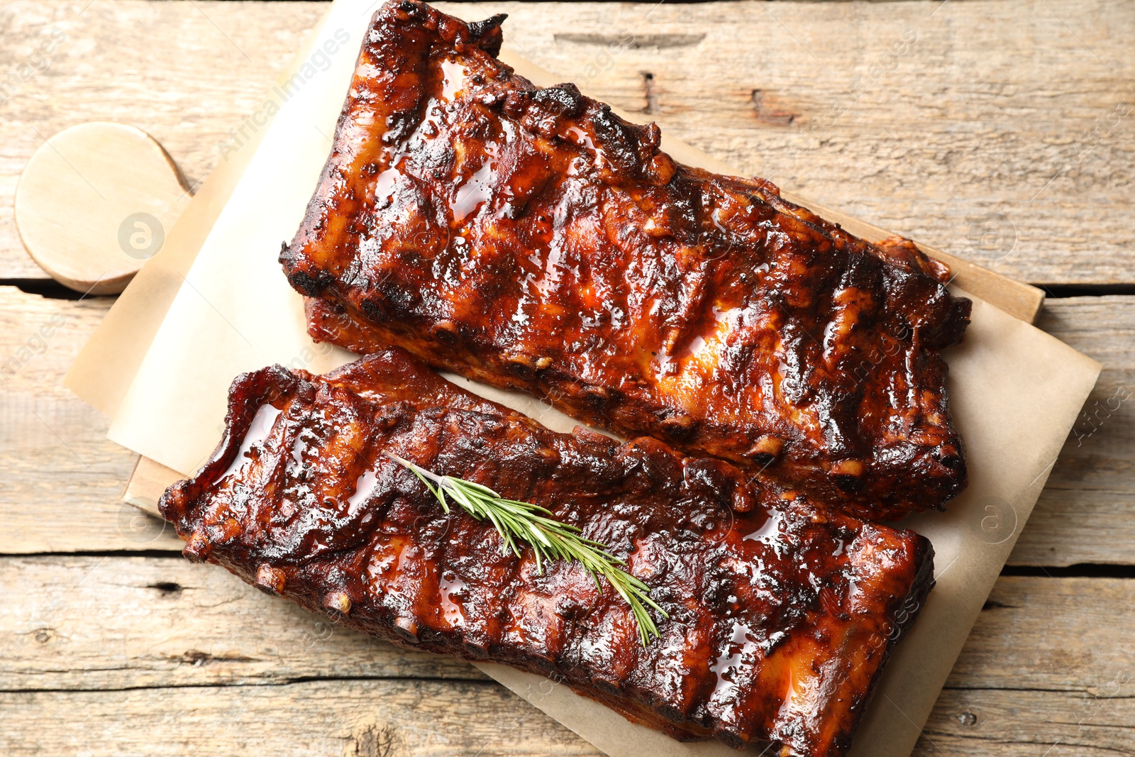Tasty roasted pork ribs served with rosemary on wooden table, top view Photo of Tasty roasted pork ribs served with rosemary on wooden table, top view