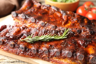 Photo of Tasty roasted pork ribs served with rosemary on wooden table, closeup