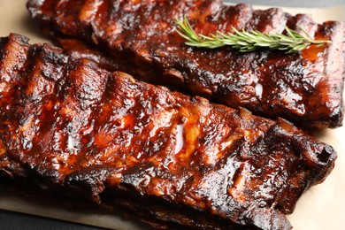Photo of Tasty roasted pork ribs served with rosemary on table, closeup