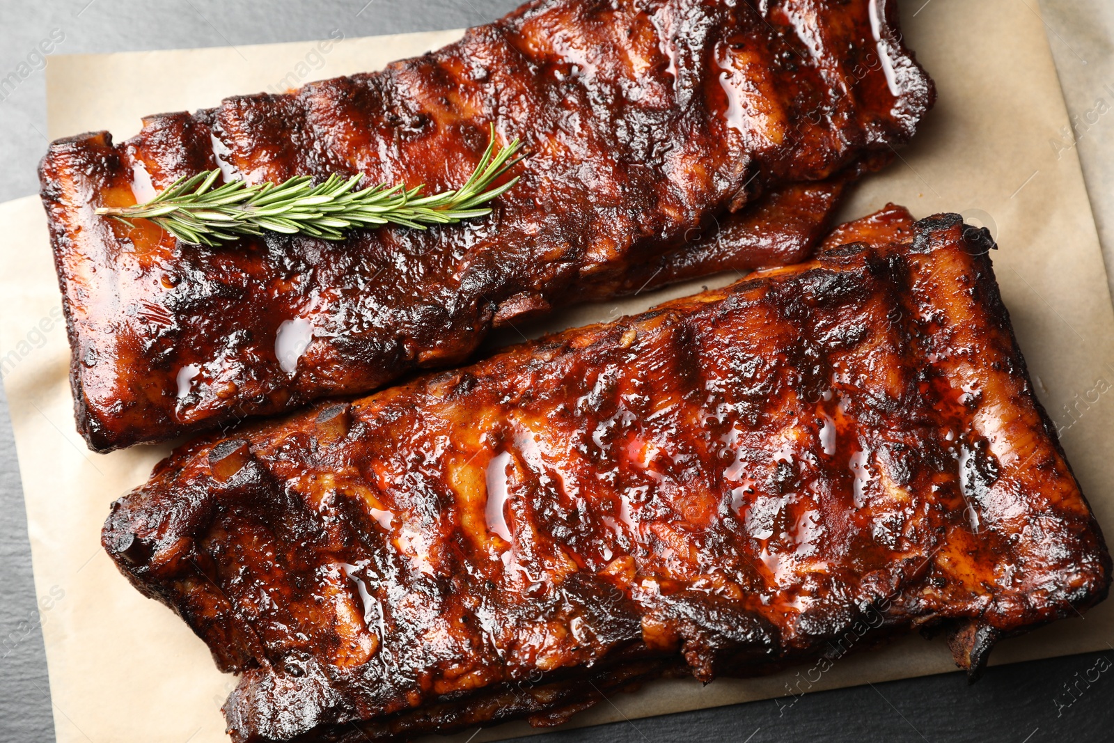 Tasty roasted pork ribs served with rosemary on black table, top view Photo of Tasty roasted pork ribs served with rosemary on black table, top view