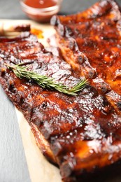 Photo of Tasty roasted pork ribs served with rosemary on black table, closeup