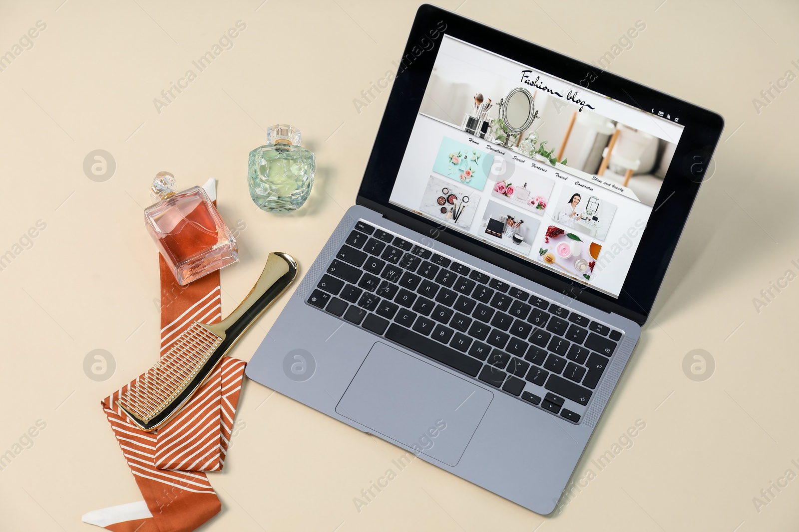 Laptop with fashion blog web site, accessories and perfumes on beige background, above view Photo of Laptop with fashion blog web site, accessories and perfumes on beige background, above view