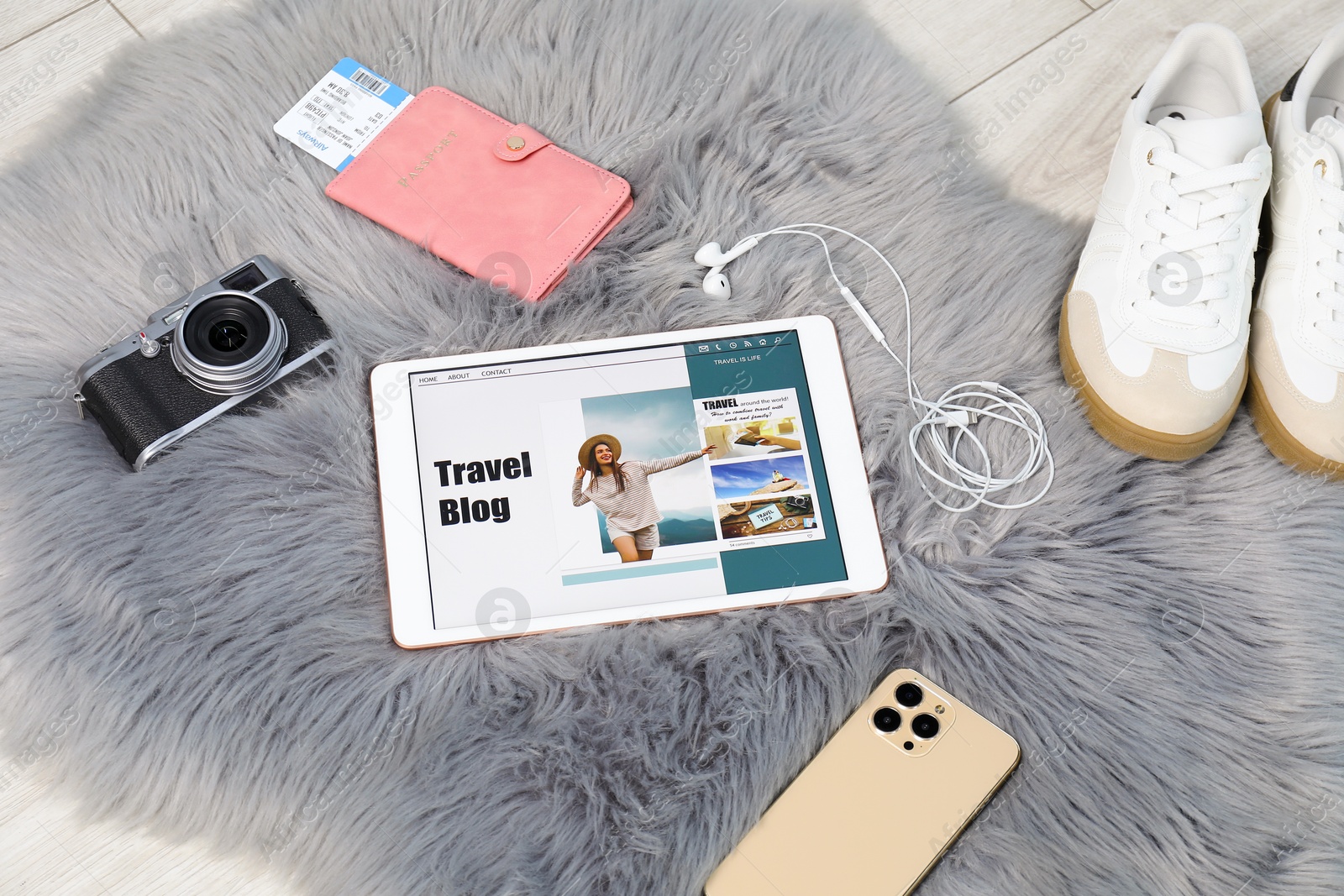 Tablet with travel blog web site and different stuff on floor indoors, above view Photo of Tablet with travel blog web site and different stuff on floor indoors, above view