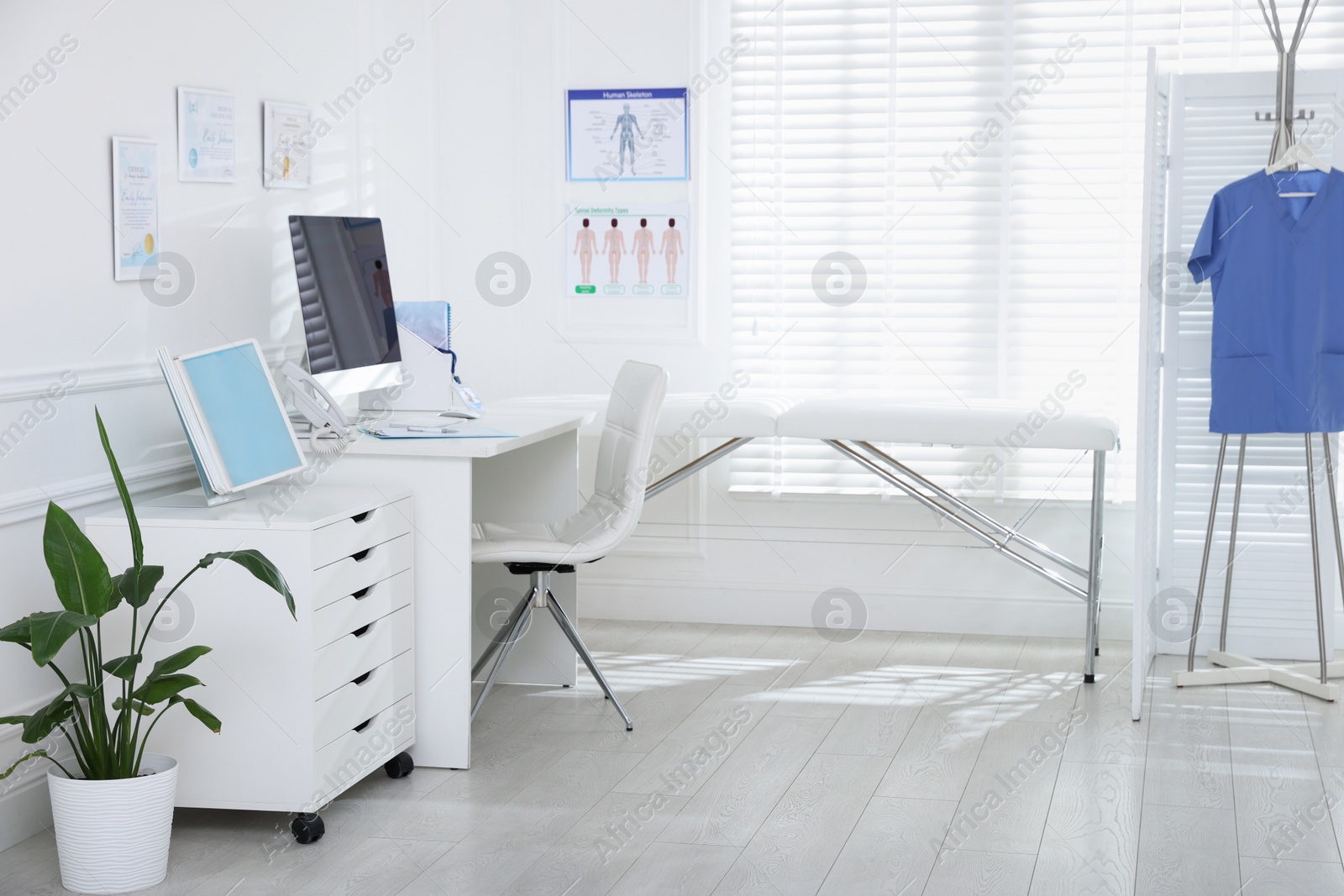 Photo of Doctor's workplace with modern computer and examination table in medical office
