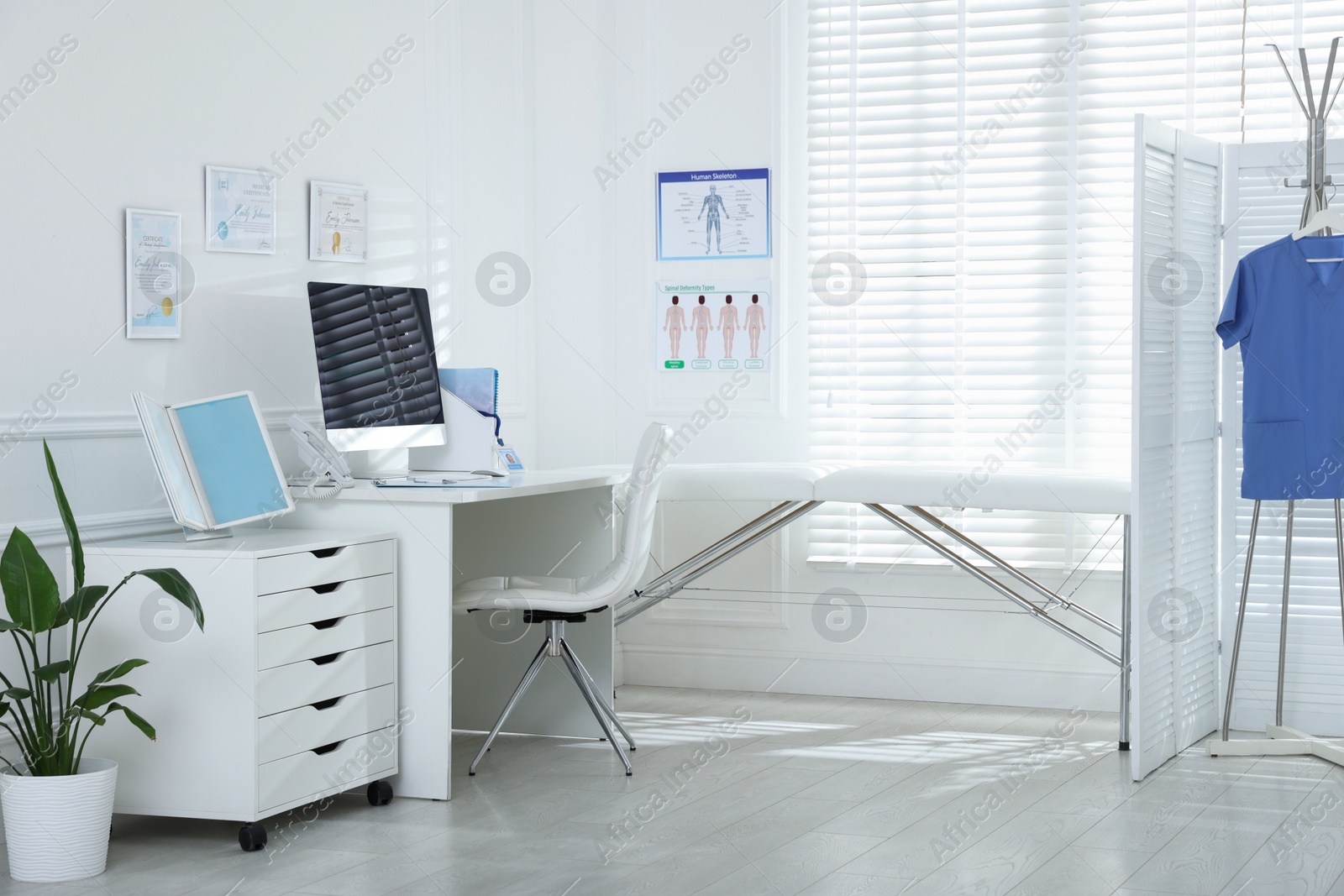 Photo of Doctor's workplace with modern computer and examination table in medical office