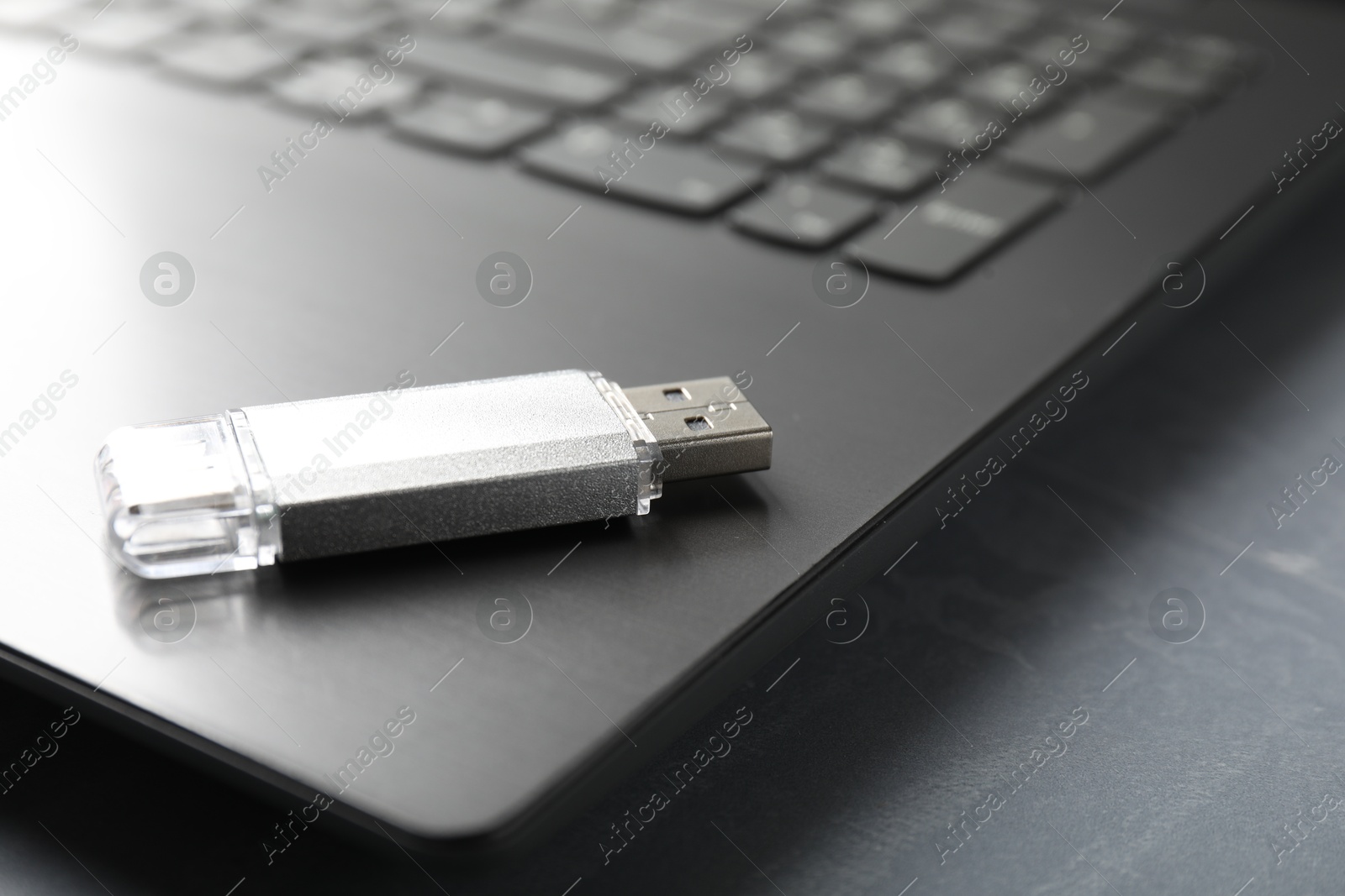 Usb flash drive and laptop on grey textured table, closeup Photo of Usb flash drive and laptop on grey textured table, closeup