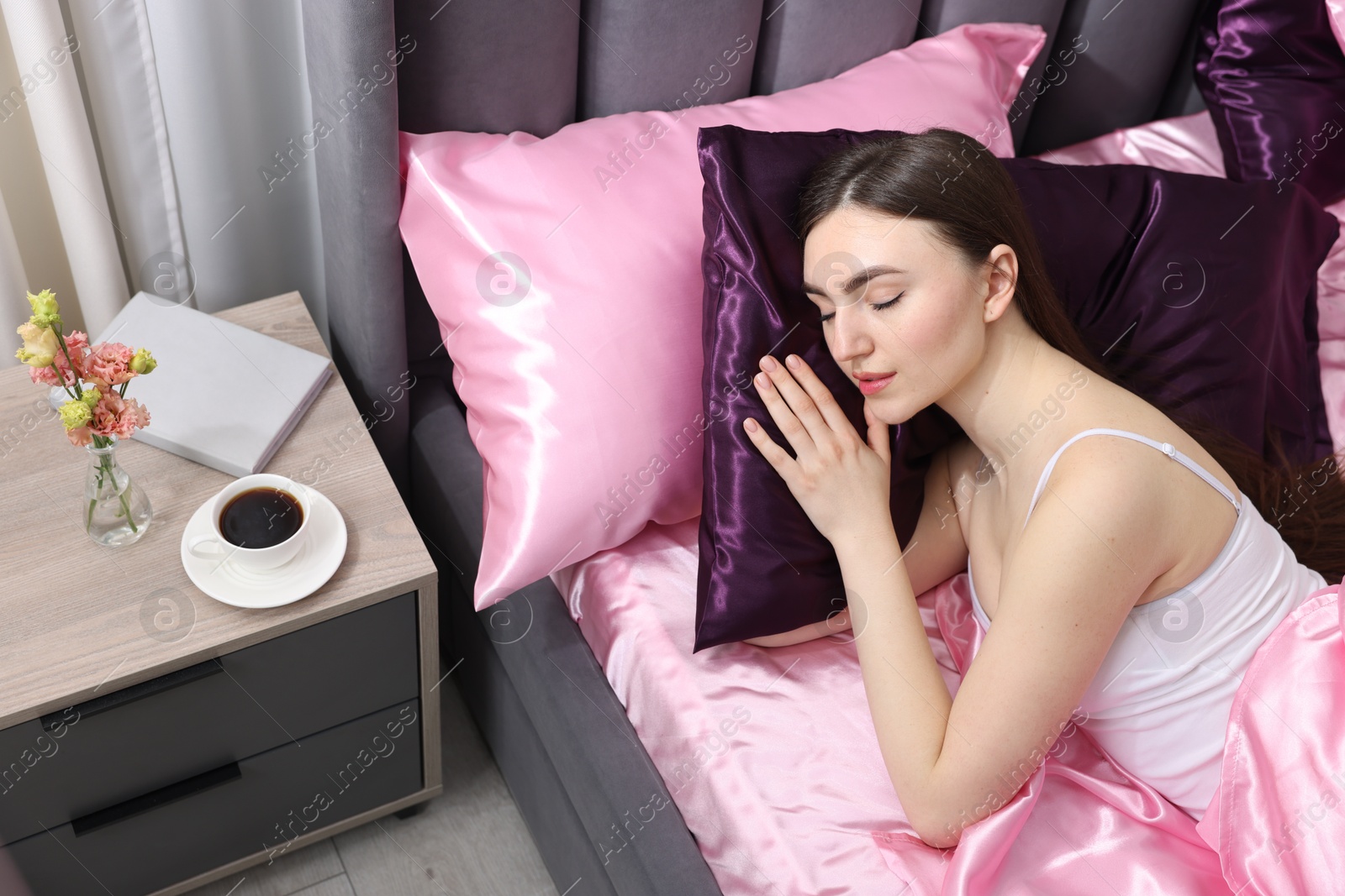 Woman sleeping in bed with silk linens indoors Photo of Woman sleeping in bed with silk linens indoors