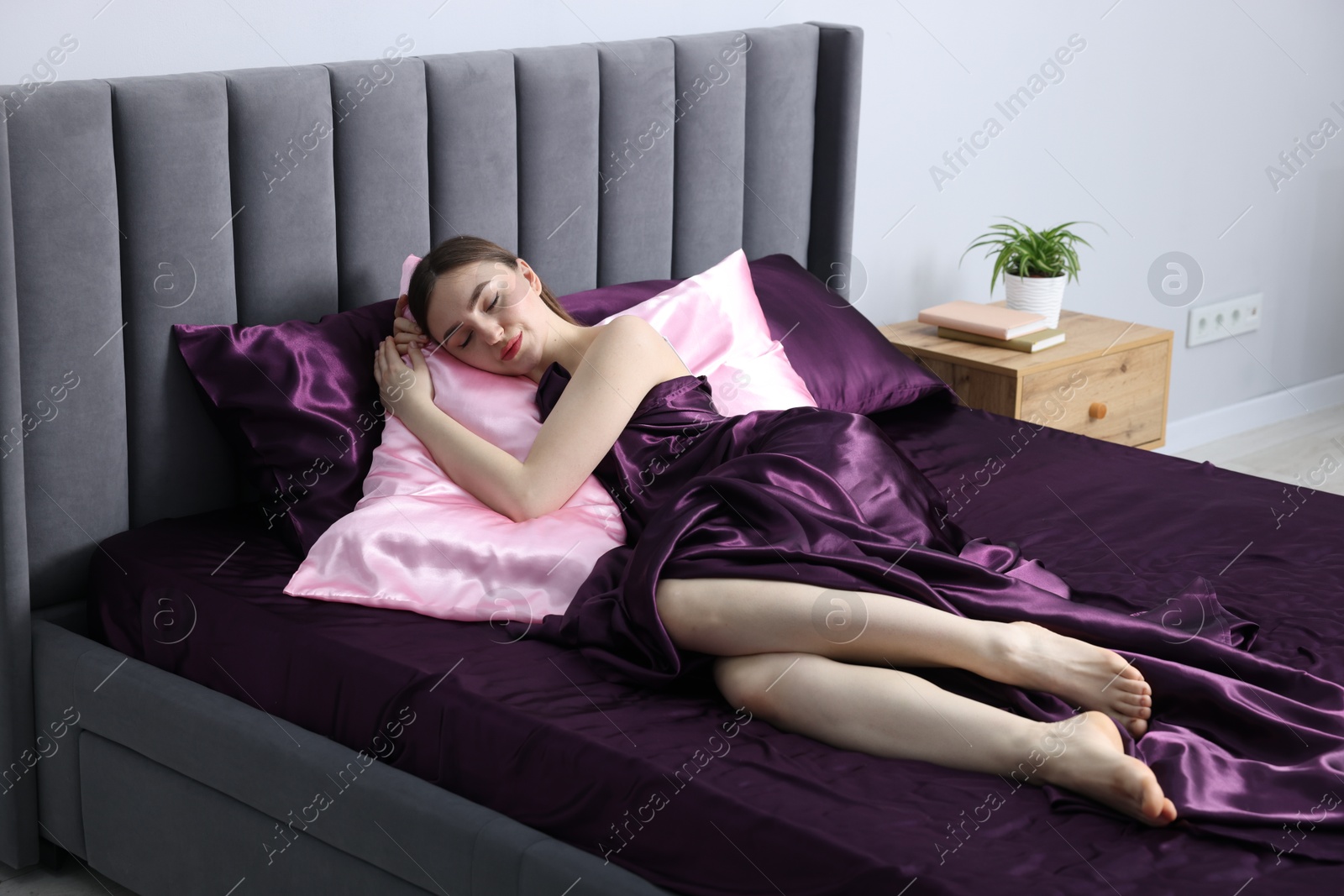 Woman sleeping in bed with silk linens indoors Photo of Woman sleeping in bed with silk linens indoors