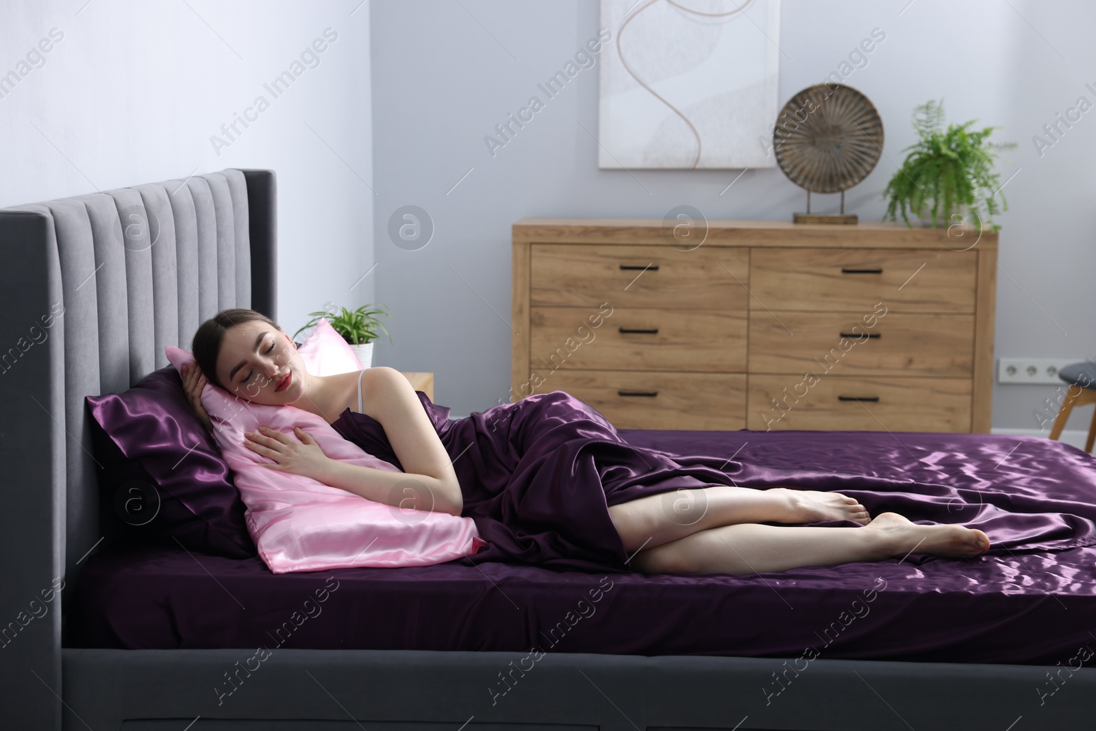 Woman sleeping in bed with silk linens indoors Photo of Woman sleeping in bed with silk linens indoors