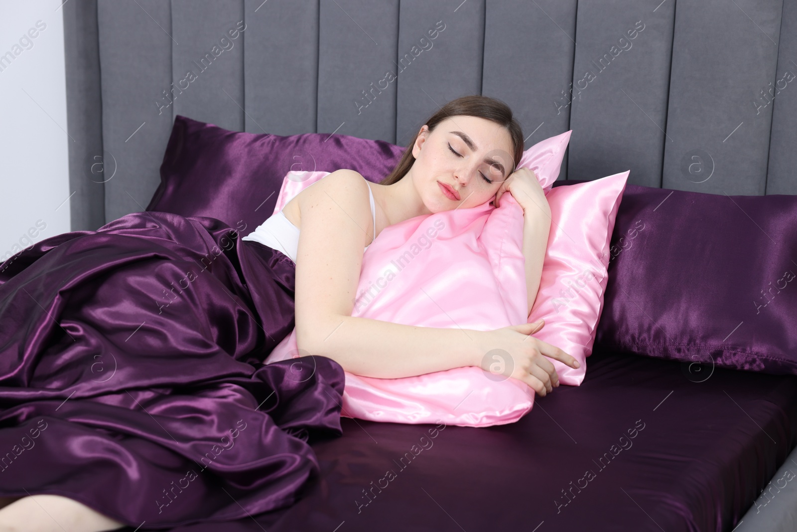 Woman sleeping in bed with silk linens indoors Photo of Woman sleeping in bed with silk linens indoors
