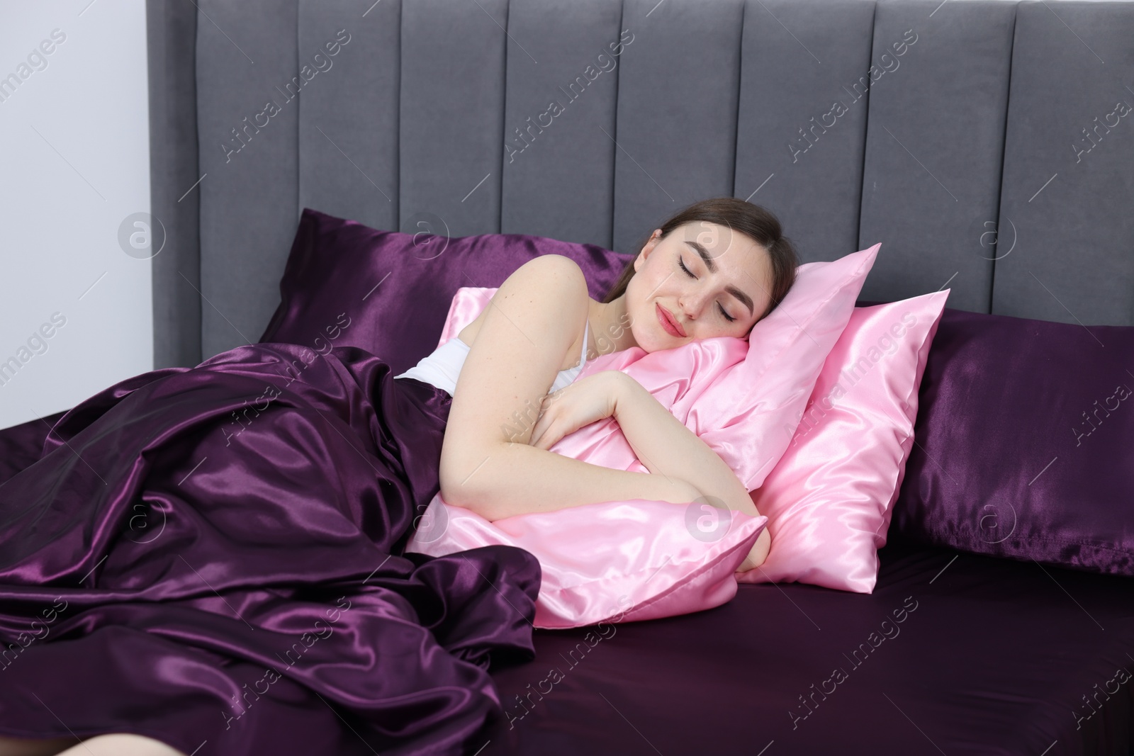 Woman sleeping in bed with silk linens indoors Photo of Woman sleeping in bed with silk linens indoors