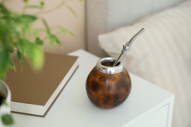 Photo of Traditional yerba mate tea and book on bedside table indoors