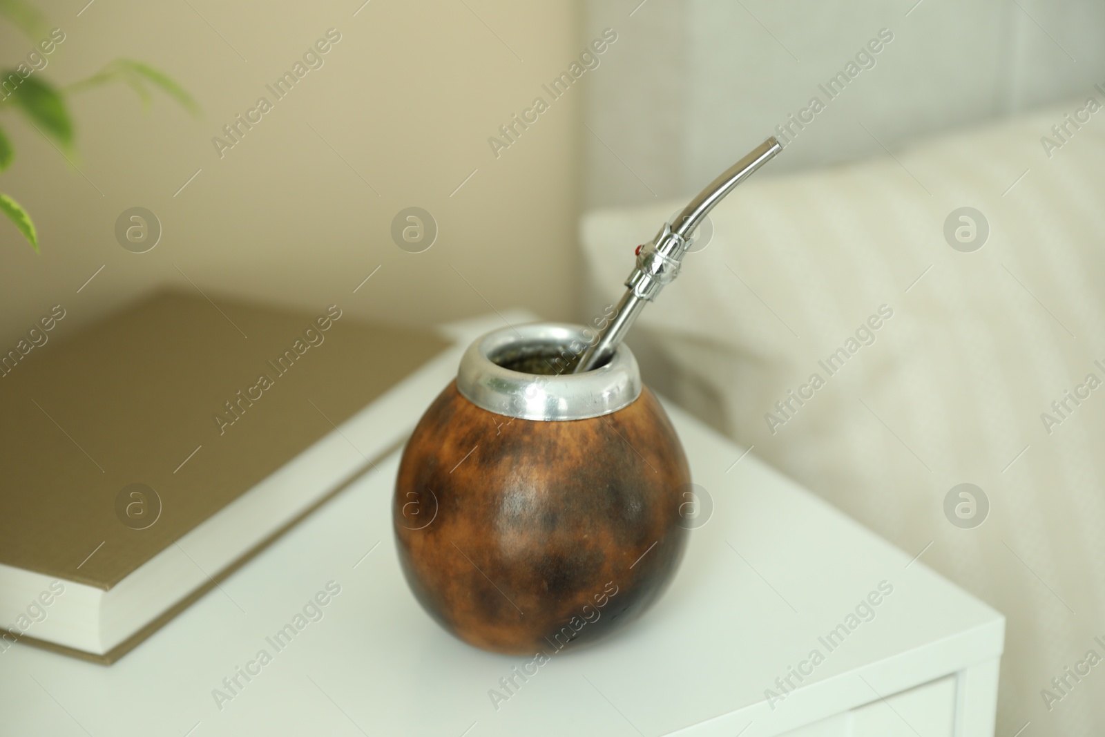Traditional yerba mate tea and book on bedside table indoors Photo of Traditional yerba mate tea and book on bedside table indoors