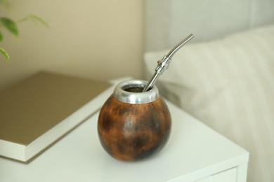 Photo of Traditional yerba mate tea and book on bedside table indoors