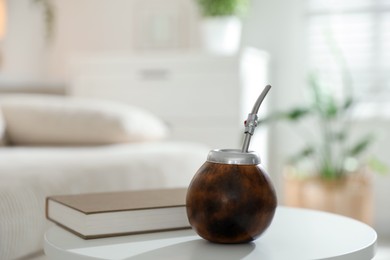 Photo of Traditional yerba mate tea and book on white table indoors