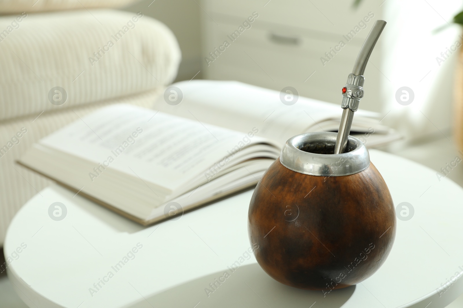 Traditional yerba mate tea and book on white table indoors Photo of Traditional yerba mate tea and book on white table indoors