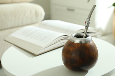 Photo of Traditional yerba mate tea and book on white table indoors