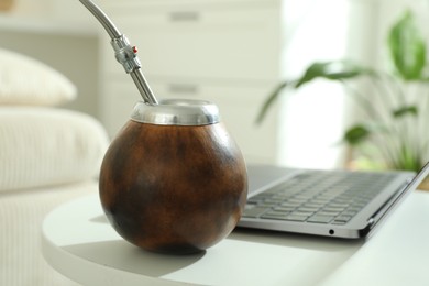 Photo of Traditional yerba mate tea and laptop on white table indoors, closeup