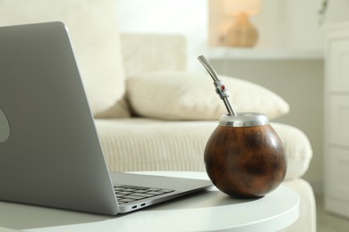Photo of Traditional yerba mate tea and laptop on white table indoors