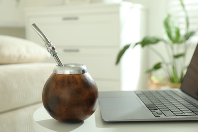Photo of Traditional yerba mate tea and laptop on white table indoors