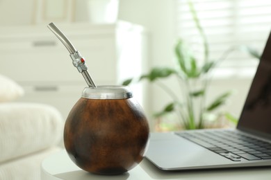 Photo of Traditional yerba mate tea and laptop on white table indoors