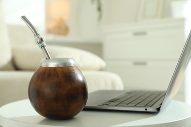 Photo of Traditional yerba mate tea and laptop on white table indoors
