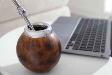Photo of Traditional yerba mate tea and laptop on white table, closeup