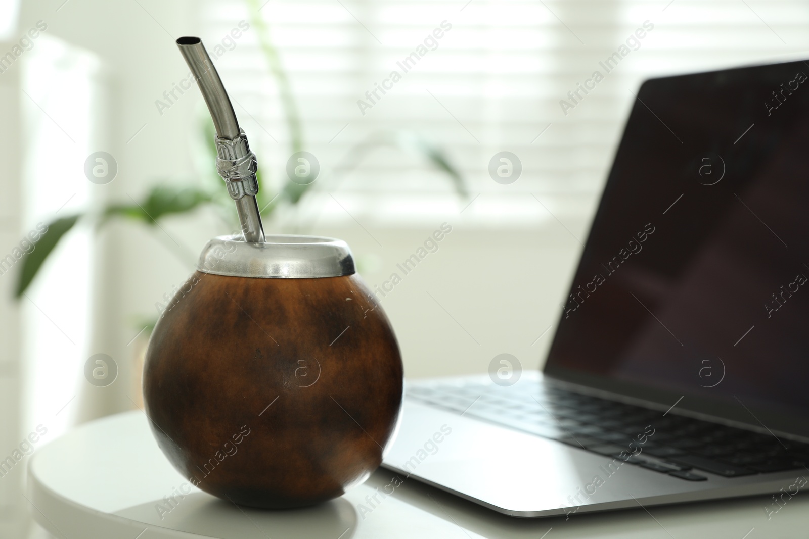 Traditional yerba mate tea and laptop on white table, closeup Photo of Traditional yerba mate tea and laptop on white table, closeup