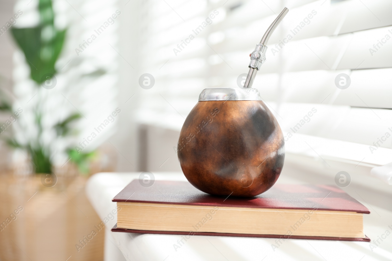 Traditional yerba mate tea and book on windowsill indoors Photo of Traditional yerba mate tea and book on windowsill indoors