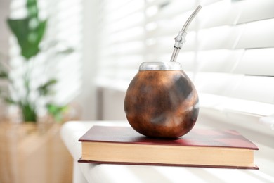 Photo of Traditional yerba mate tea and book on windowsill indoors