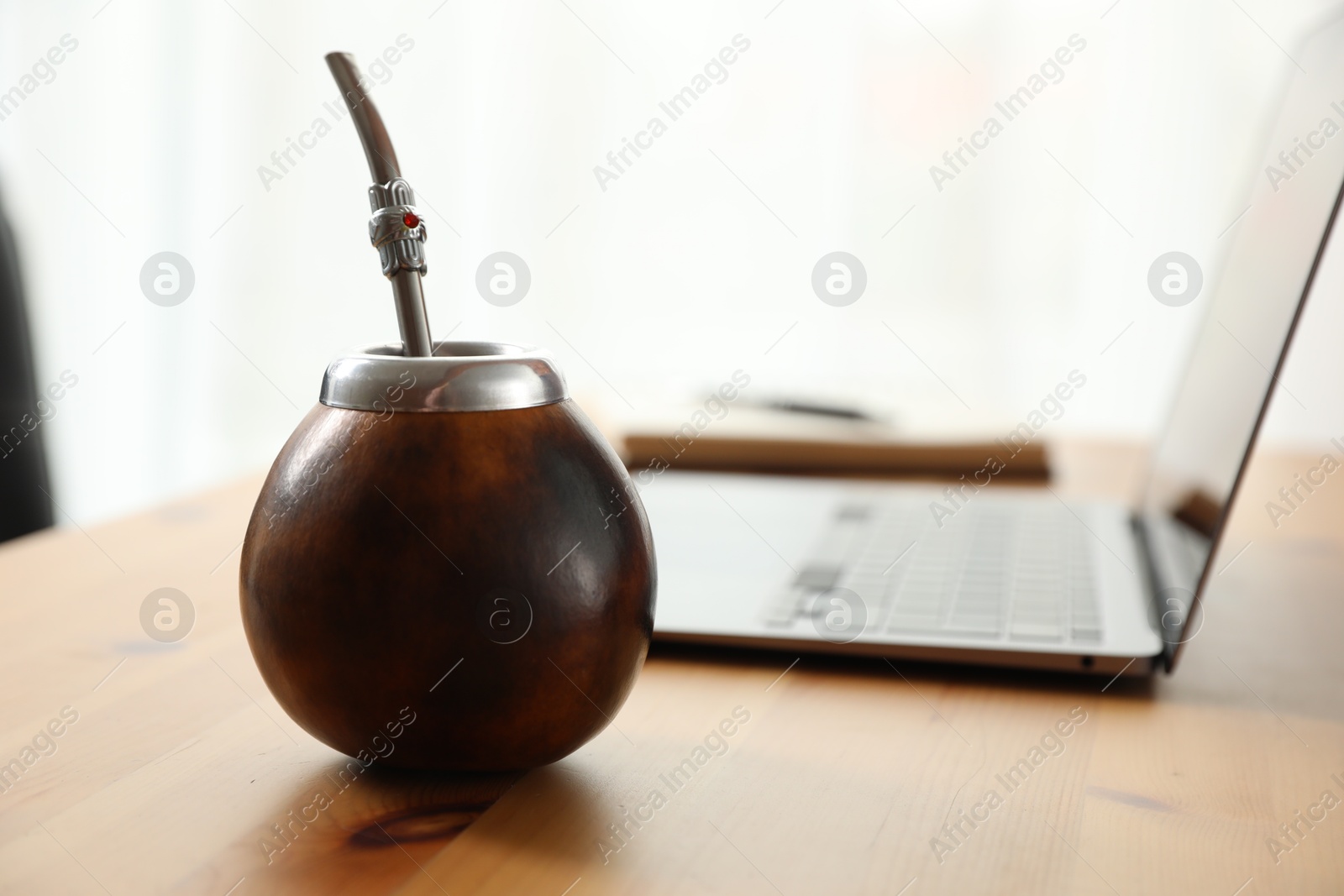 Traditional yerba mate tea and laptop on wooden table, closeup Photo of Traditional yerba mate tea and laptop on wooden table, closeup