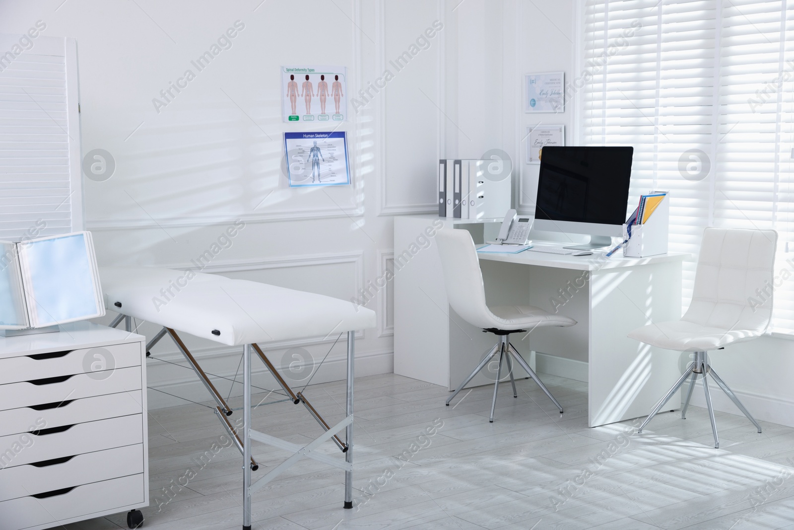 Doctor's workplace with modern computer and examination table in medical office Photo of Doctor's workplace with modern computer and examination table in medical office