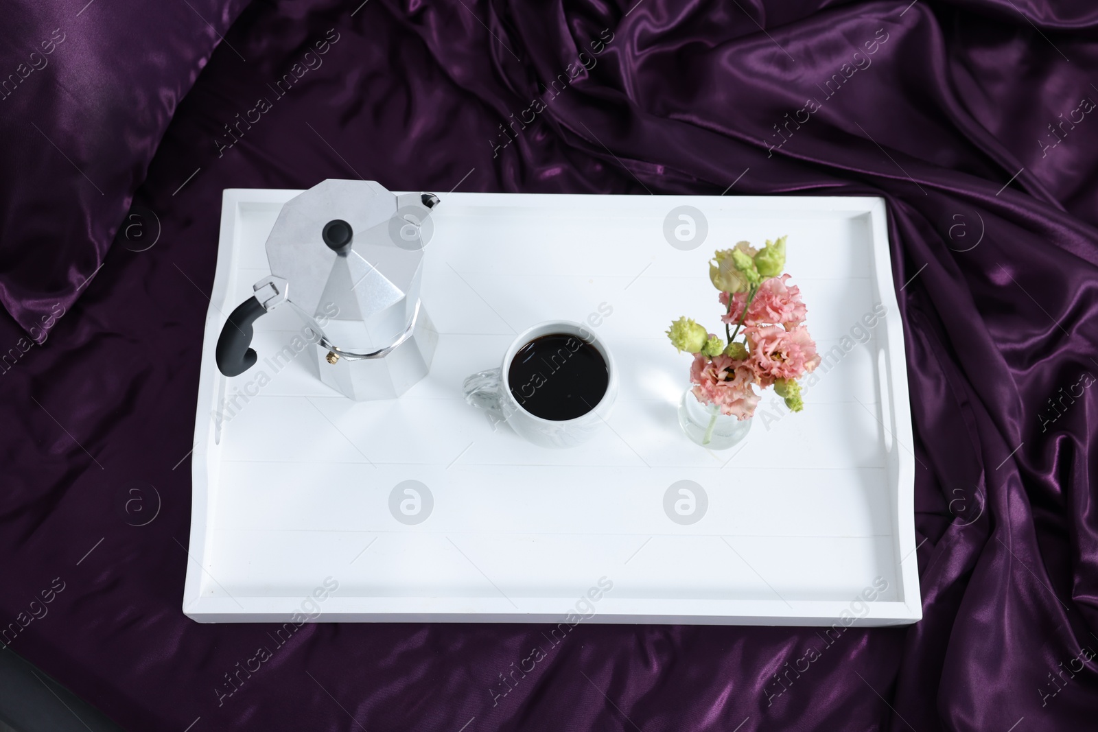 Purple silk linens, tray with coffee and flowers on bed, above view Photo of Purple silk linens, tray with coffee and flowers on bed, above view
