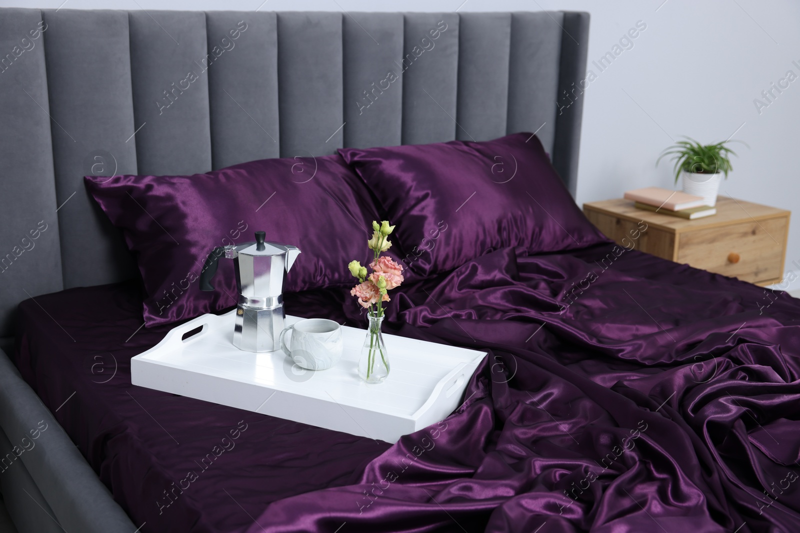 Purple silk linens, tray with coffee and flowers on bed indoors Photo of Purple silk linens, tray with coffee and flowers on bed indoors