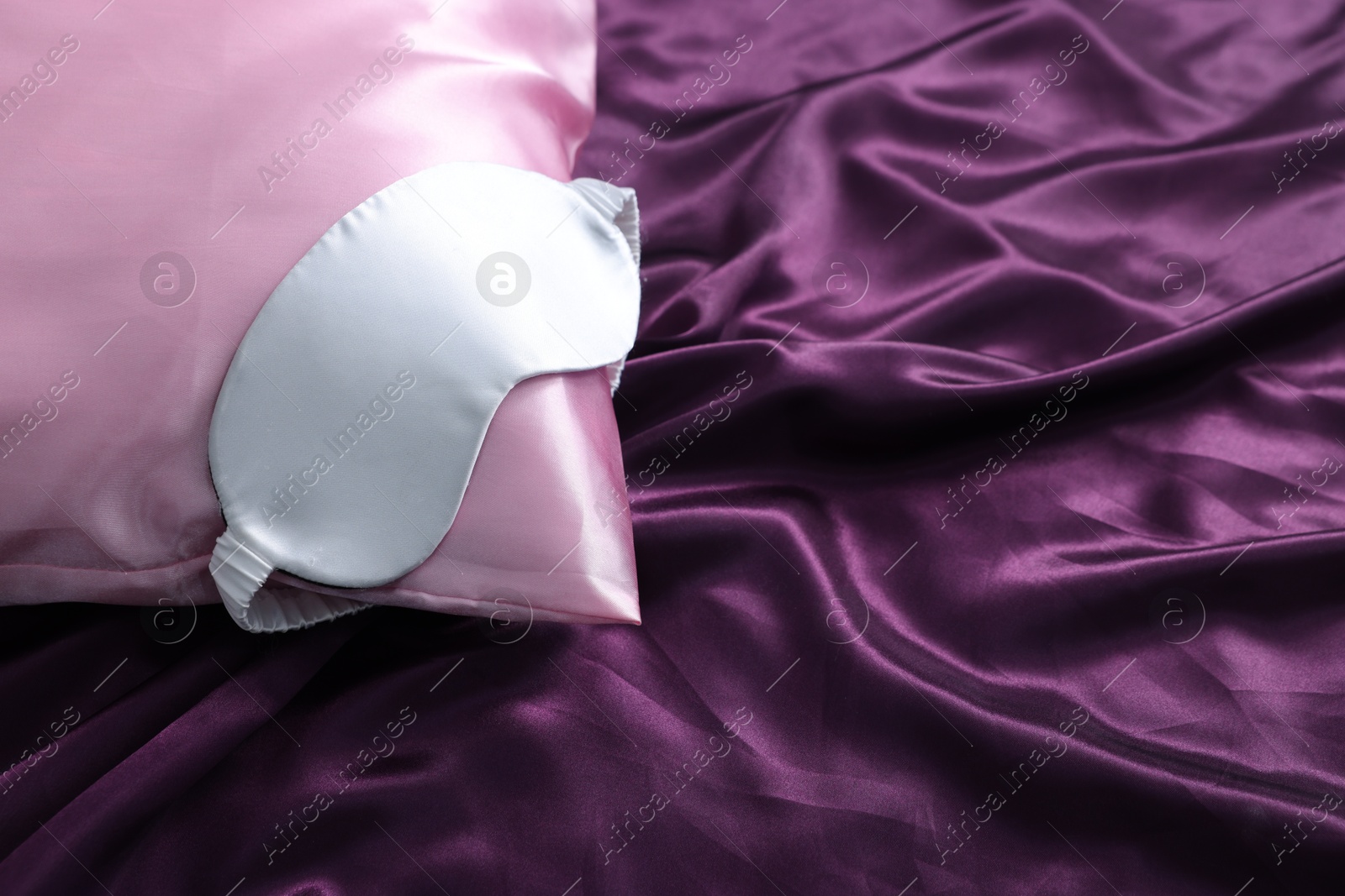 Luxury silk bed linens and pillow with sleep mask, closeup Photo of Luxury silk bed linens and pillow with sleep mask, closeup