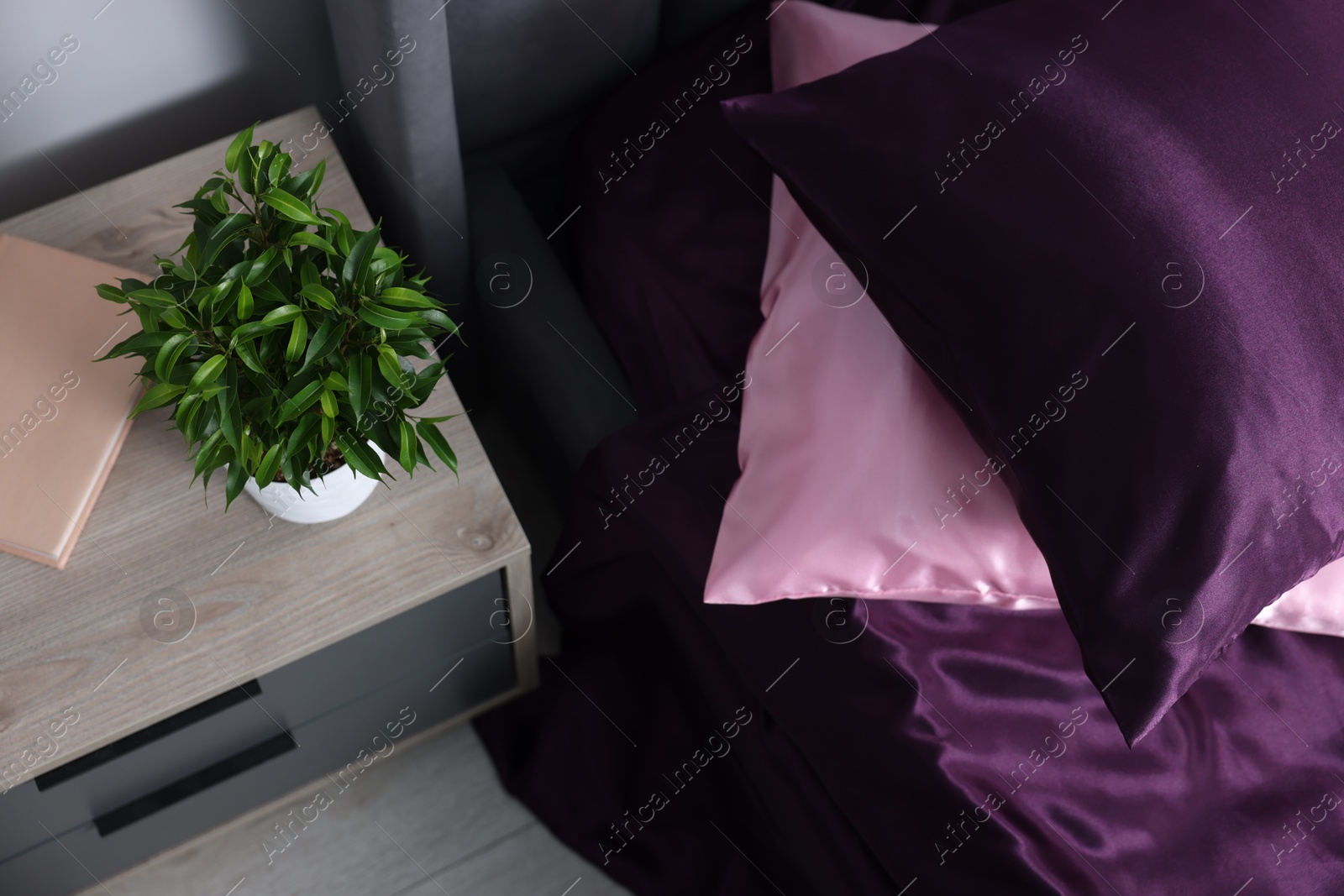Luxury silk linens on bed and nightstand at home, above view Photo of Luxury silk linens on bed and nightstand at home, above view