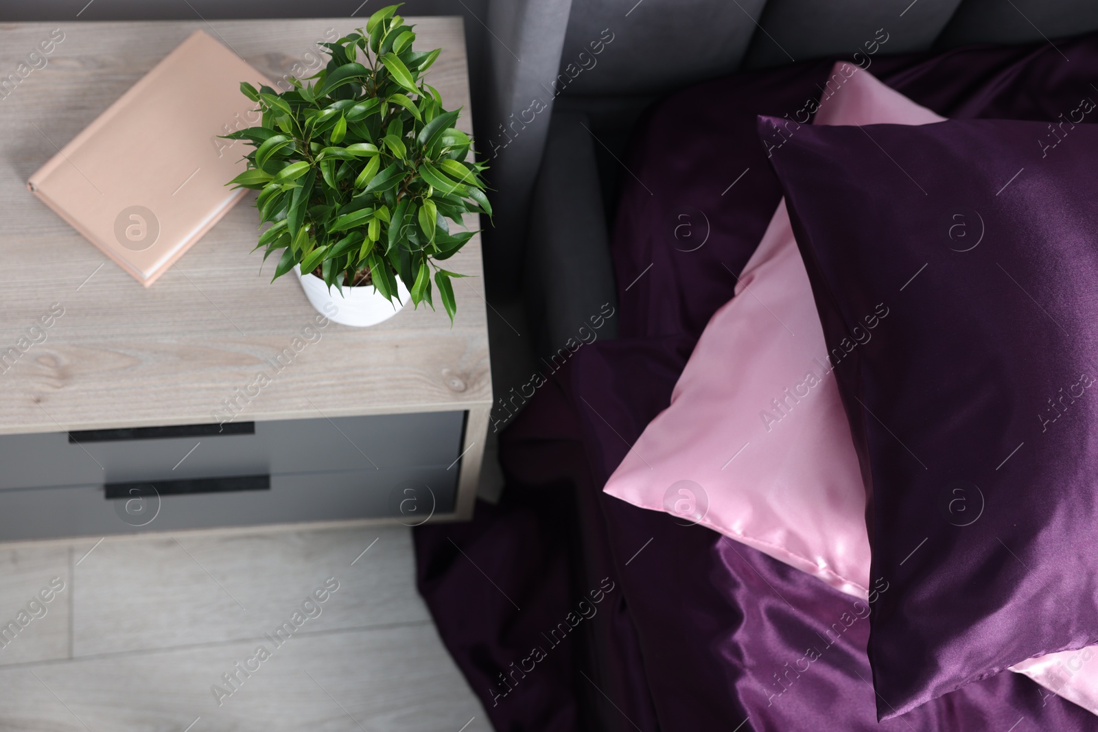 Luxury silk linens on bed and nightstand at home, above view Photo of Luxury silk linens on bed and nightstand at home, above view