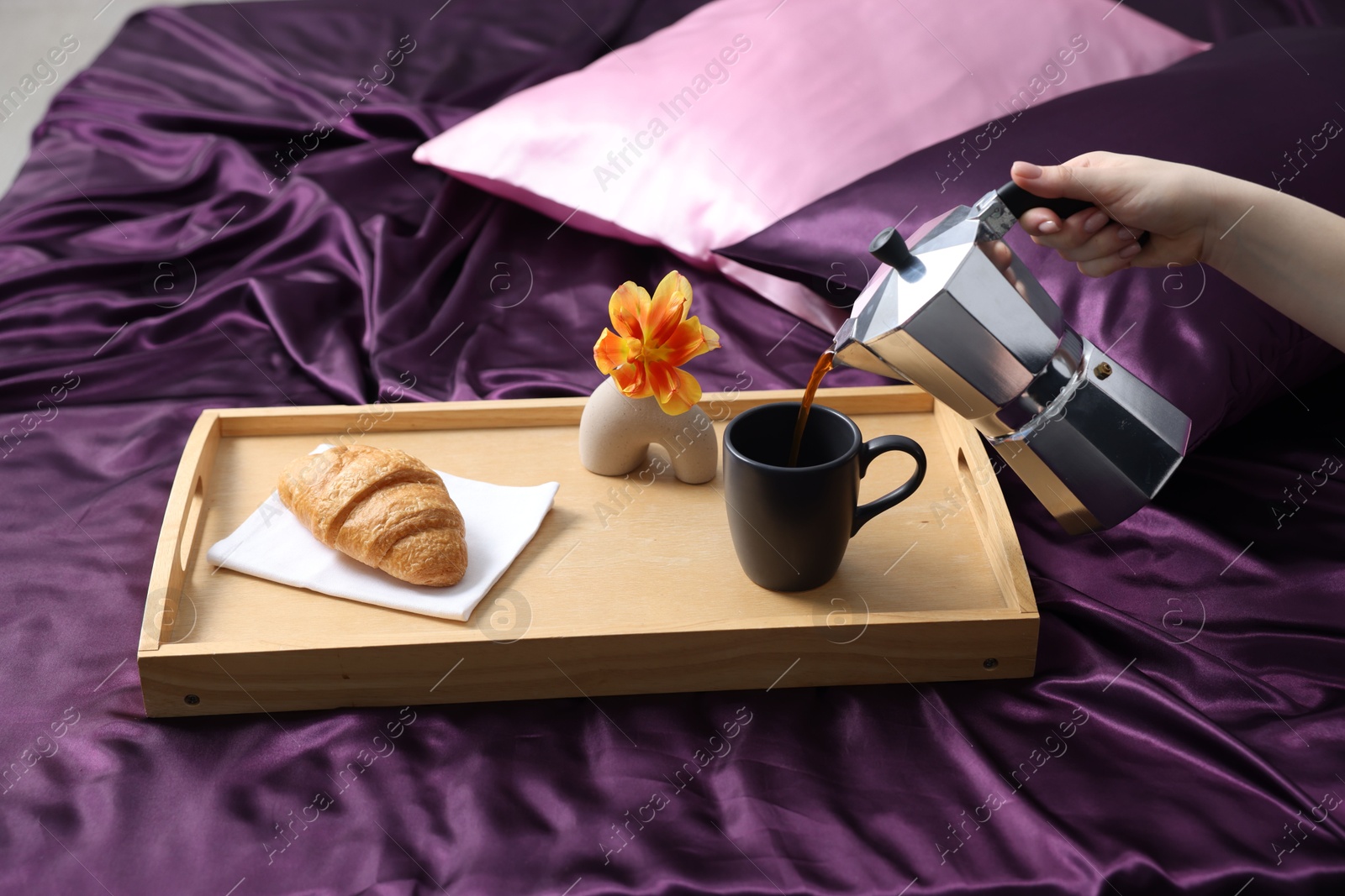 Woman pouring coffee from moka pot into cup on bed with purple silk linens, closeup Photo of Woman pouring coffee from moka pot into cup on bed with purple silk linens, closeup