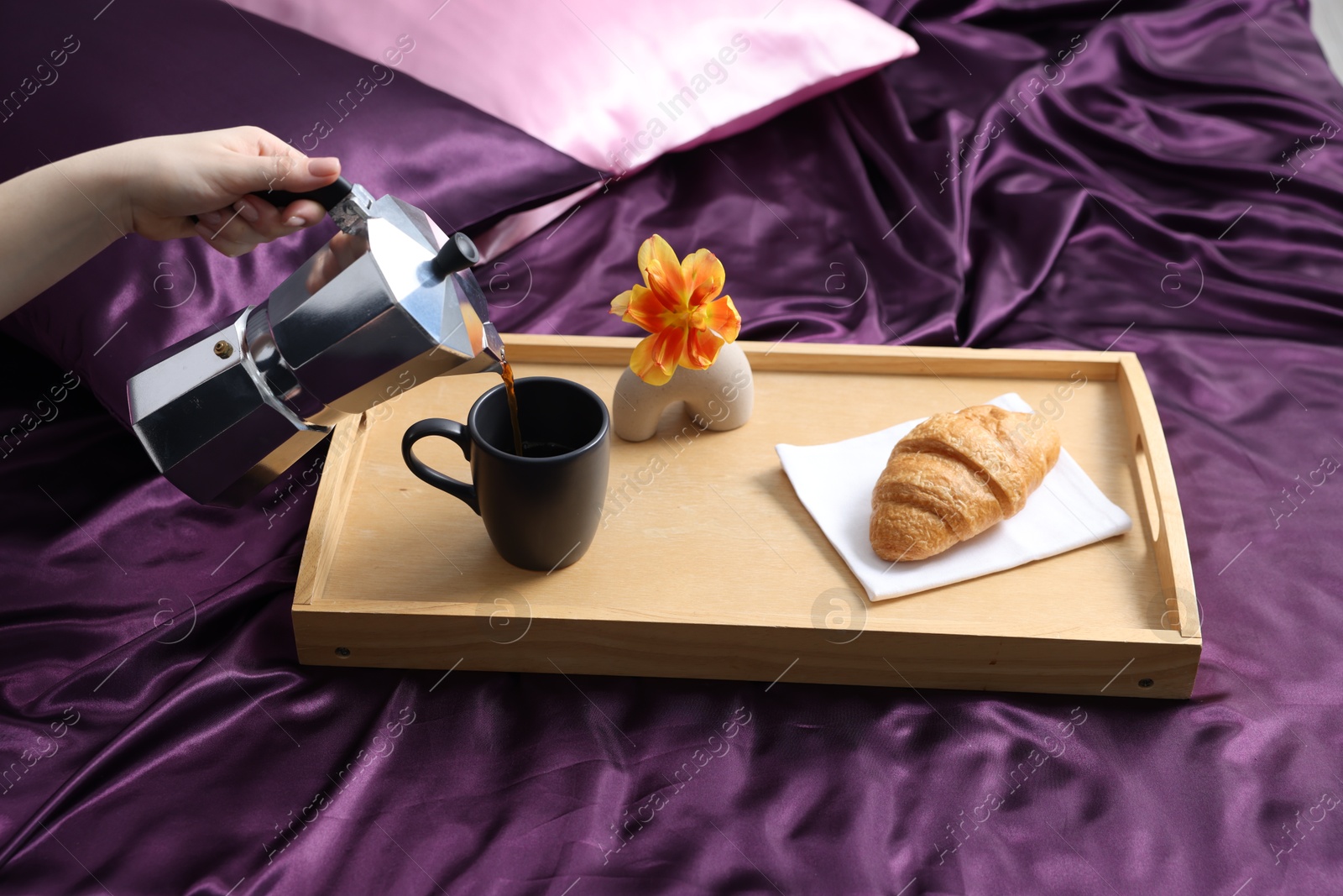 Woman pouring coffee from moka pot into cup on bed with purple silk linens, closeup Photo of Woman pouring coffee from moka pot into cup on bed with purple silk linens, closeup