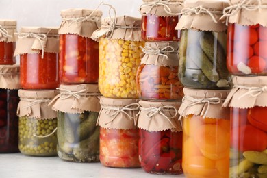 Photo of Many jars with different pickled products on light table
