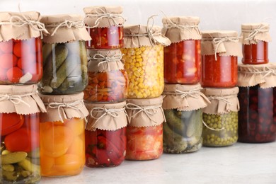 Photo of Many jars with different pickled products on light table