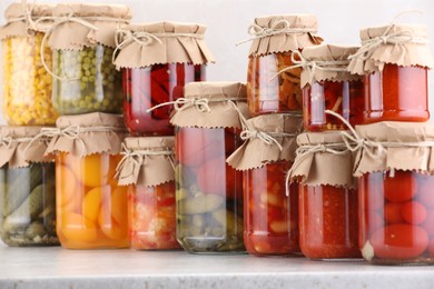 Photo of Many jars with different pickled products on light table