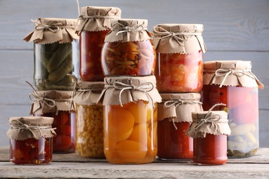 Photo of Many jars with different pickled products on wooden table