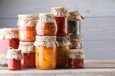 Photo of Many jars with different pickled products on wooden table