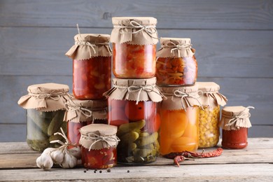 Photo of Many jars with different pickled products on wooden table